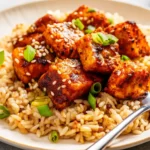 Golden crispy fried salmon bites served on a platter with lemon wedges and a side of dipping sauce.