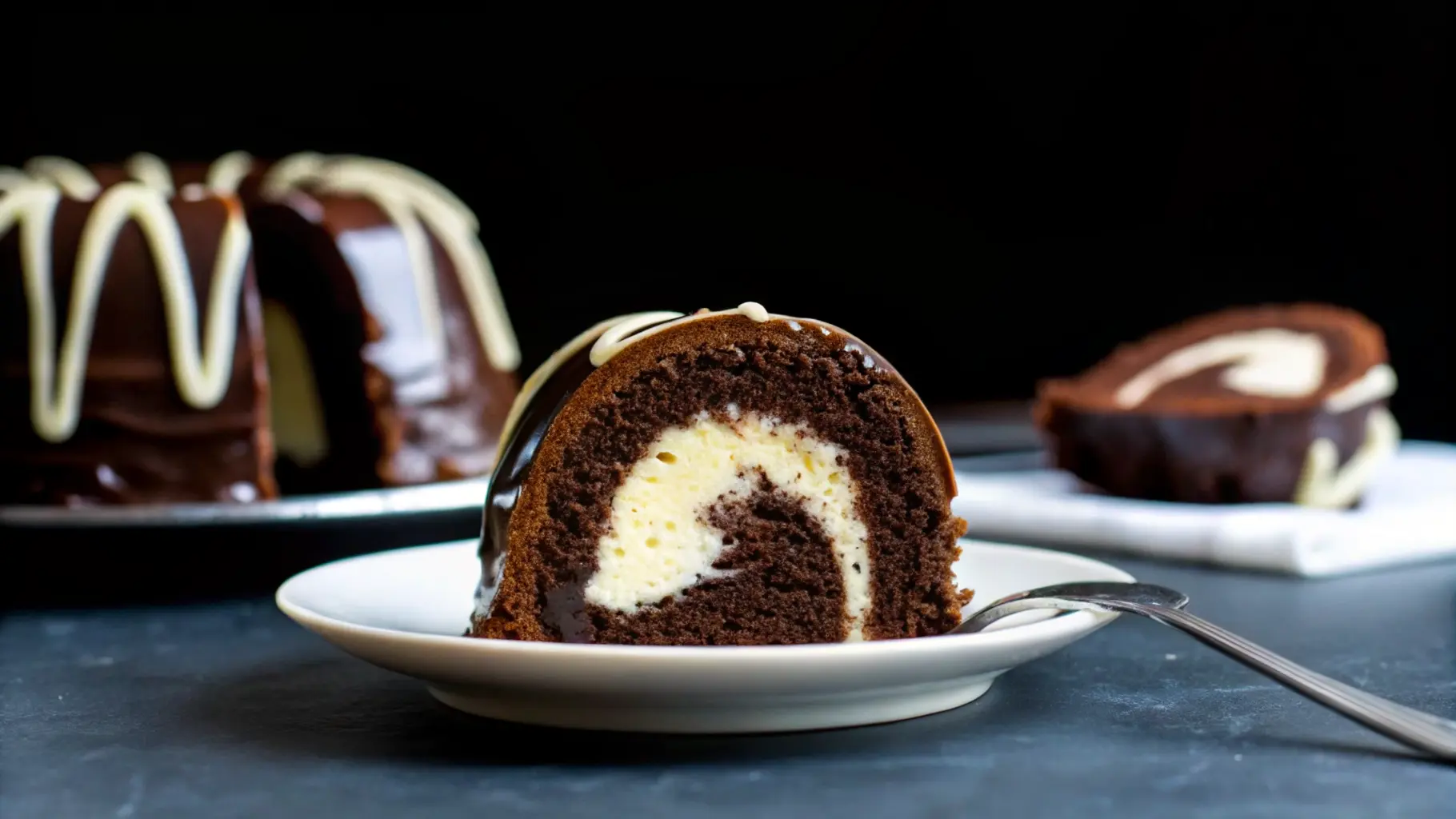 Slice of chocolate Bundt cake with cream cheese filling and chocolate glaze on a white plate