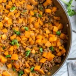 Ground beef and sweet potato skillet with melted cheese and herbs