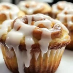 Close-up of cinnamon roll muffins topped with icing on a white plate