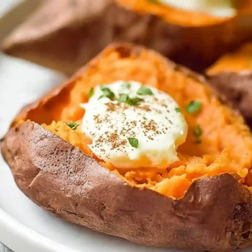 Air fryer sweet potato with crispy skin and creamy topping on a white plate