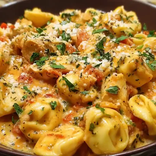 Creamy Crockpot Chicken Tortellini topped with parsley and parmesan, served in a deep brown bowl
