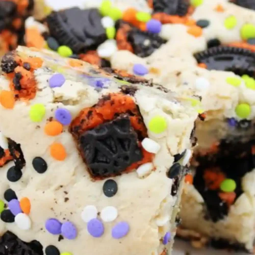 Close-up of Halloween Oreo Cake Bars topped with orange, black, and purple sprinkles and cookie chunks.