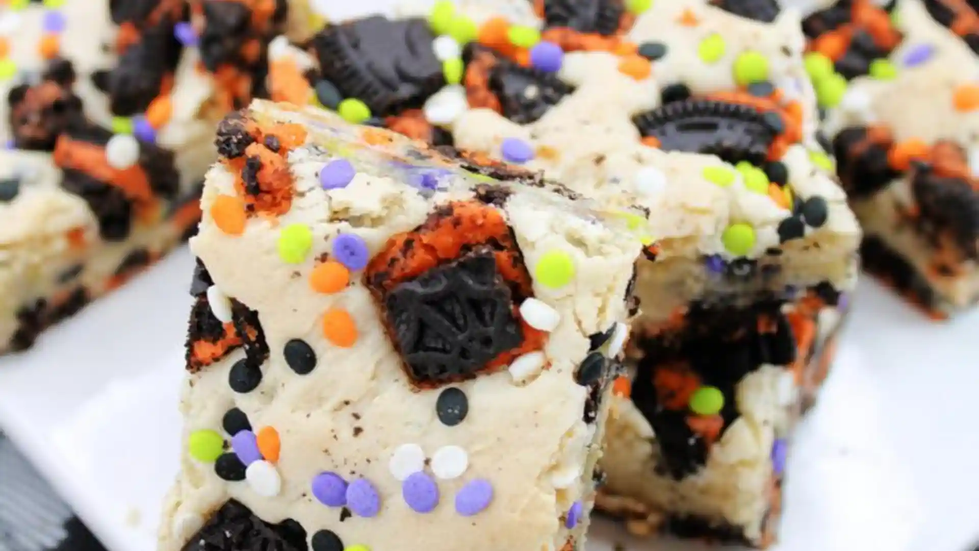 Close-up of Halloween Oreo Cake Bars topped with orange, black, and purple sprinkles and cookie chunks.
