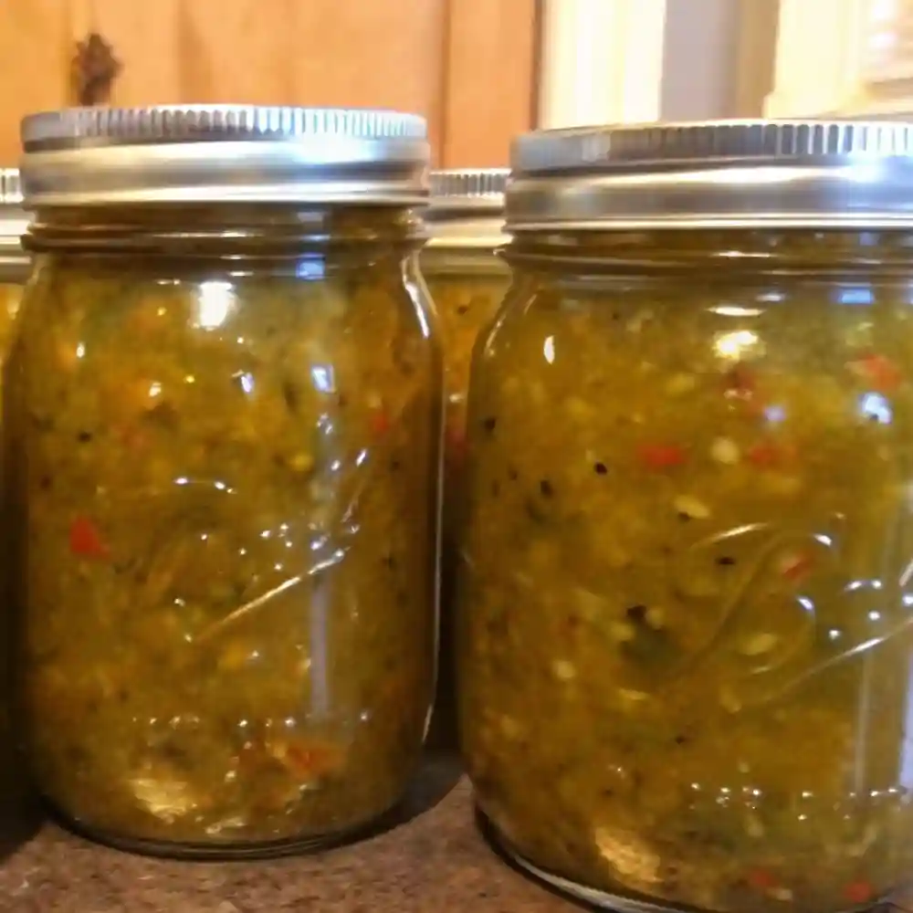 Canned jars filled with homemade zucchini relish on a kitchen counter