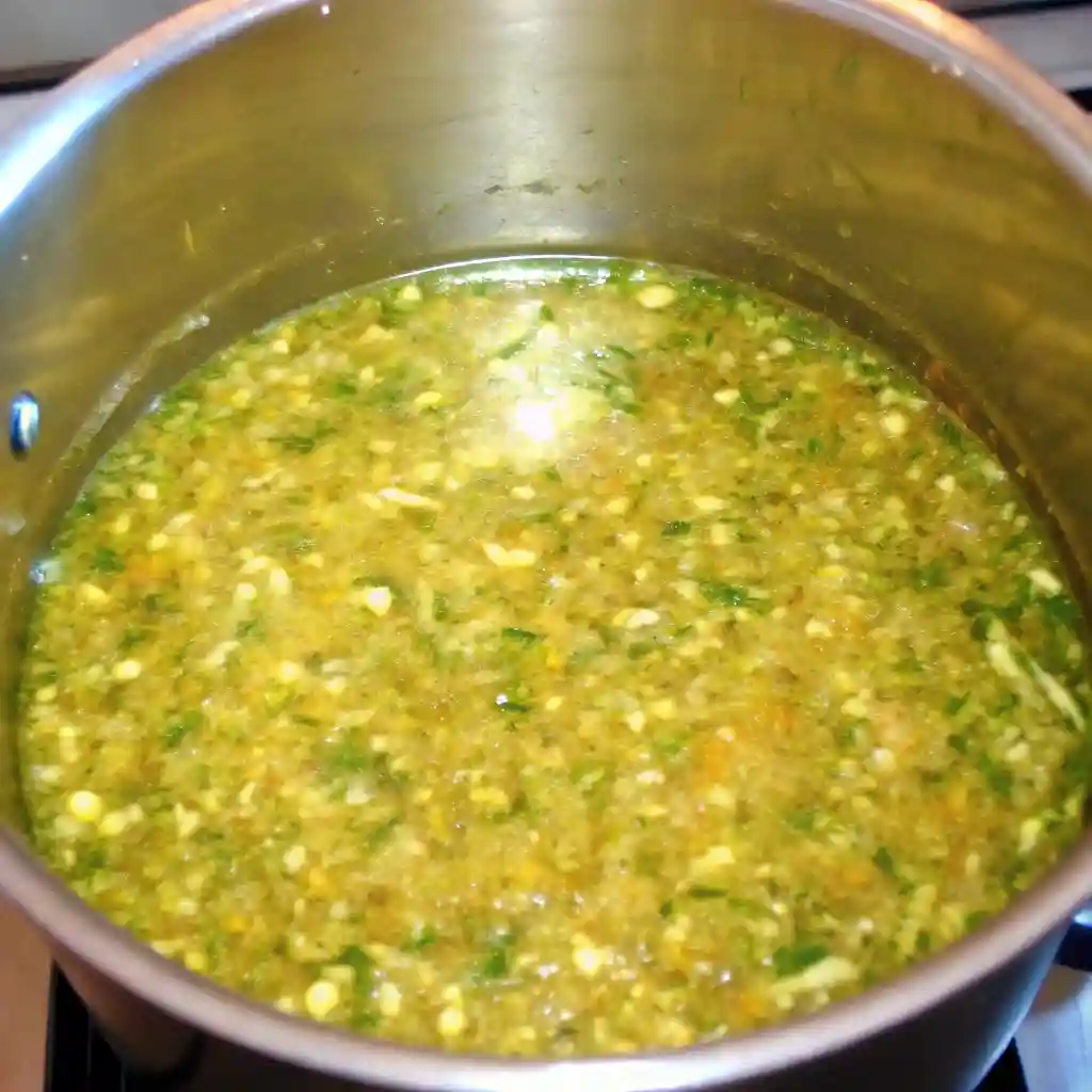 Zucchini relish mixture simmering in a stainless steel pot on the stove