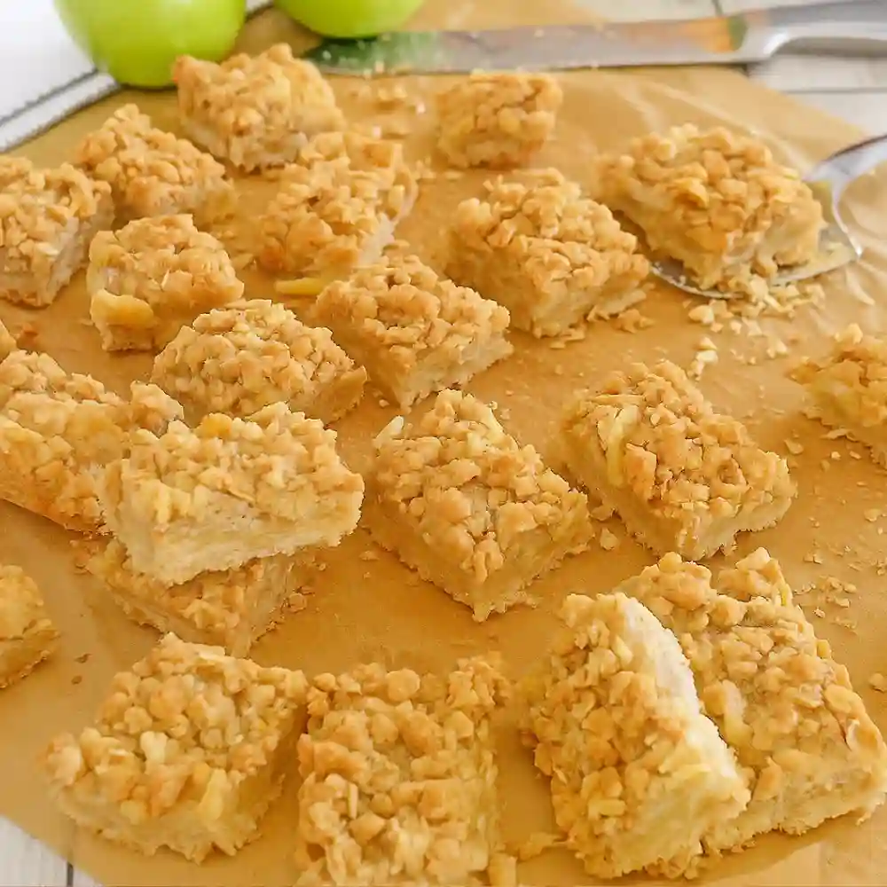 Apple crisp bars with oat streusel topping sliced into squares on parchment paper