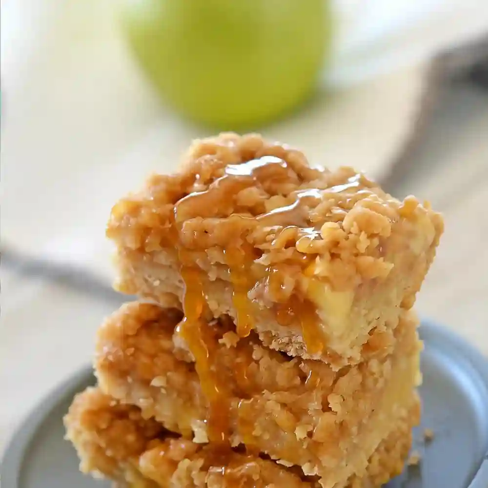 Close-up of apple crisp bars stacked with streusel topping and caramel drizzle