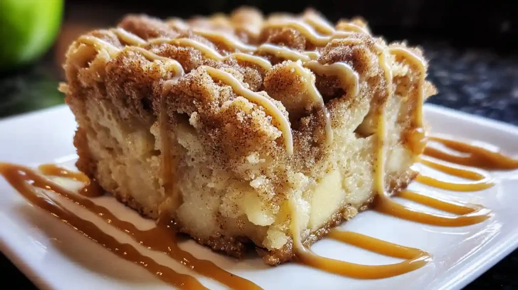 Close-up of apple crumb cake slice with cinnamon drizzle and caramel lines on white plate