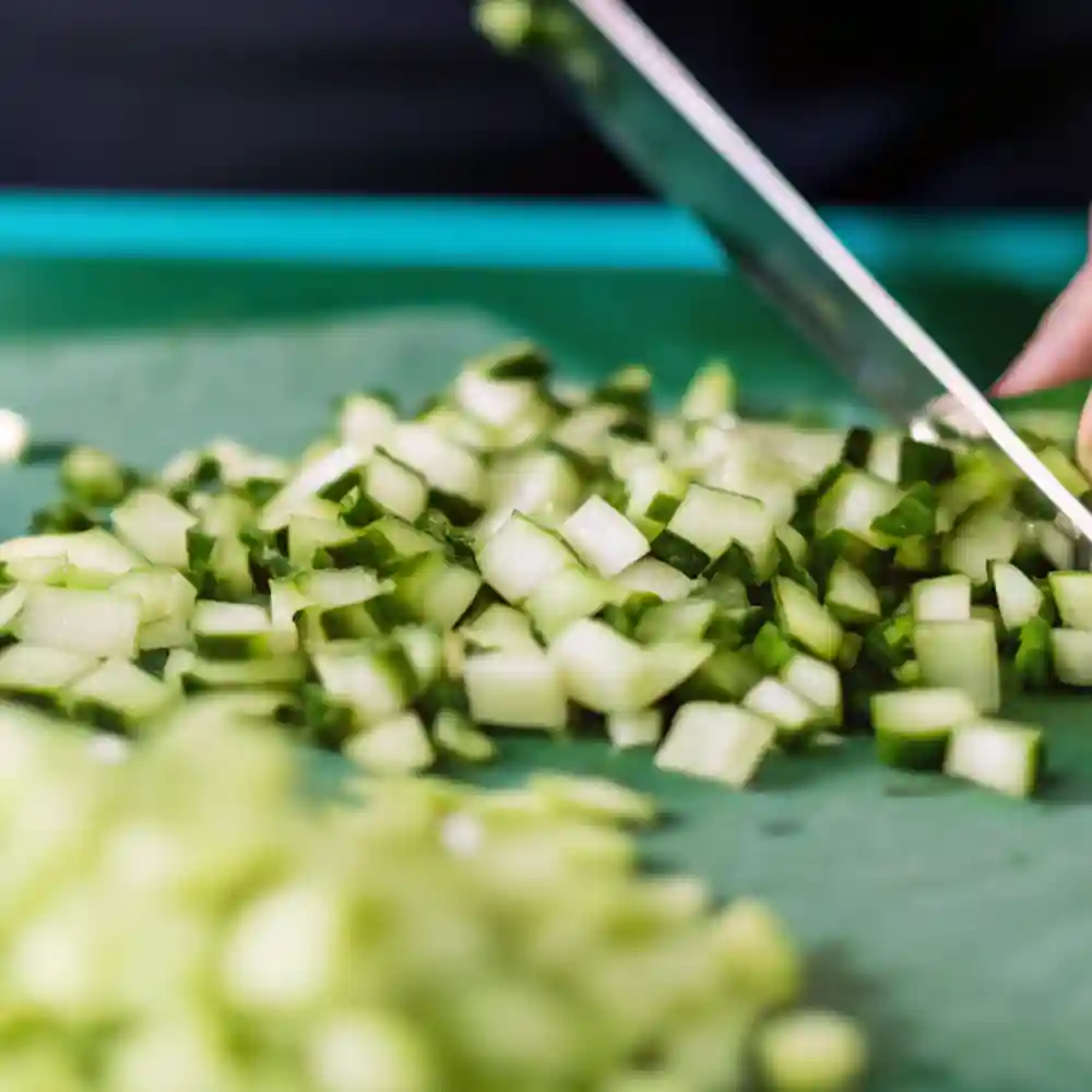 Close-up of cucumbers being diced on a cutting board for homemade sweet pickle relish