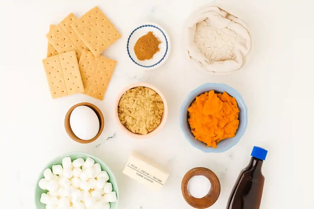 Flat lay of Pumpkin S’mores Cookies ingredients including pumpkin puree, marshmallows, flour, spices, and graham crackers