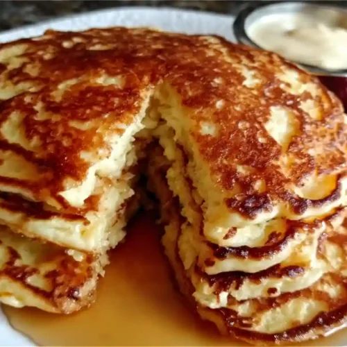Flourless cottage cheese pancakes stacked with golden edges, topped with fresh raspberries and maple syrup.